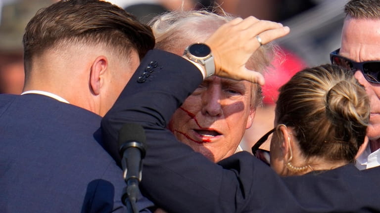 Republican presidential candidate former President Donald Trump is helped off...