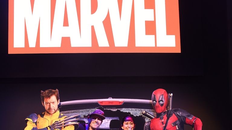 Fans pose for photos at a Marvel cardboard cutout at...