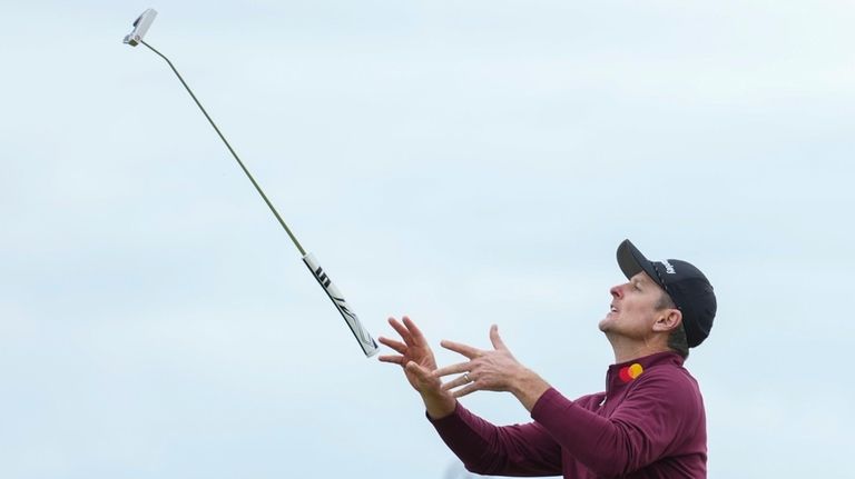 Justin Rose of England throws his putter in the air...