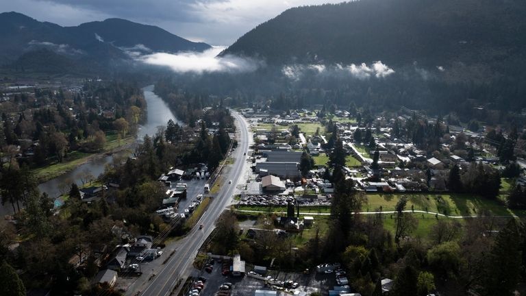 Vehicles drive down Rogue River Highway as light shines on...