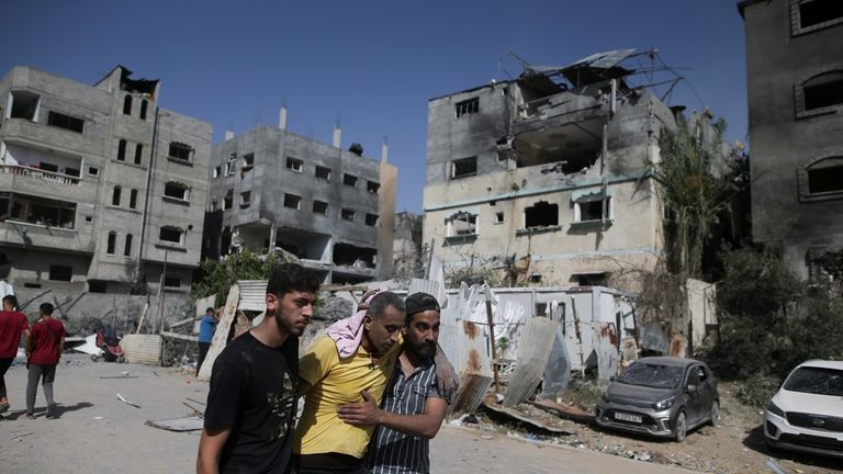 Palestinians help a wounded man after Israeli strikes in Nuseirat...