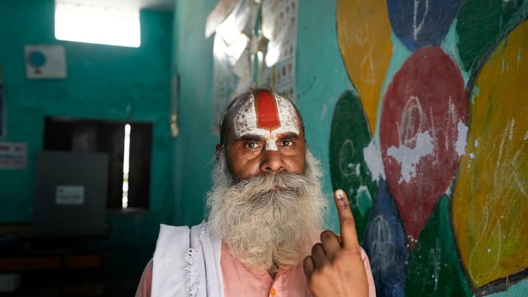 An Indian Hindu holy man shows his finger marked with...