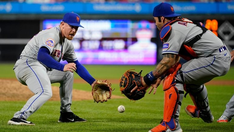 Mets pitcher Jeff Brigham, left, and catcher Francisco Alvarez chase...