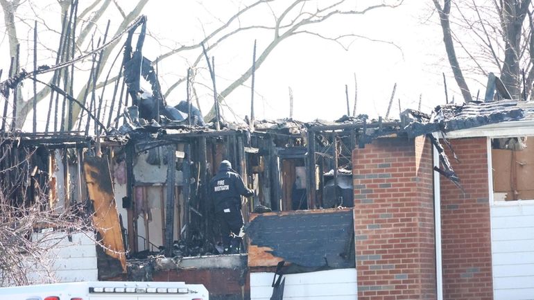 Investigators probe the scene of a fire in Plainview Sunday...