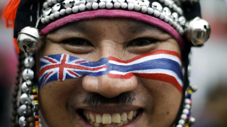 A spectator from Thailand wears traditional clothes and has his...