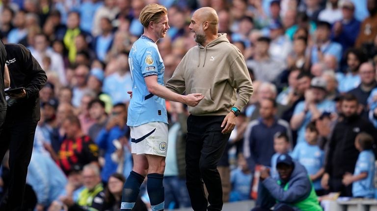 Manchester City's head coach Pep Guardiola talks with Kevin De...