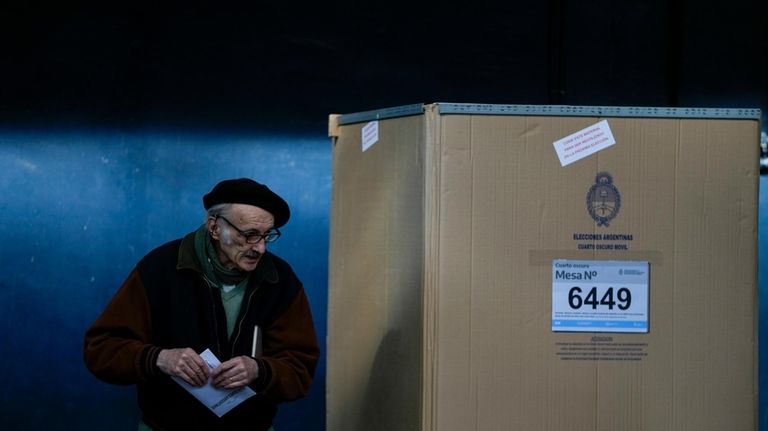 A voter holds his ballot during primary elections in Buenos...