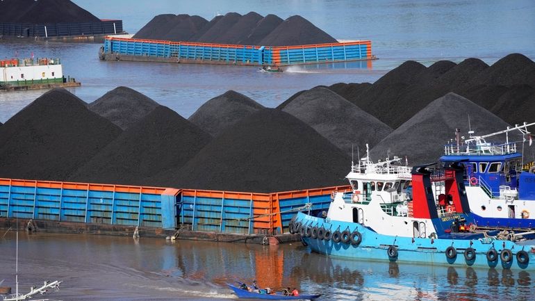 FILE- Boats cruise near barges fully loaded with coal on...