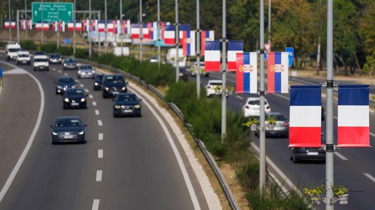 French and Serbian flags fly on lampposts on a highway...