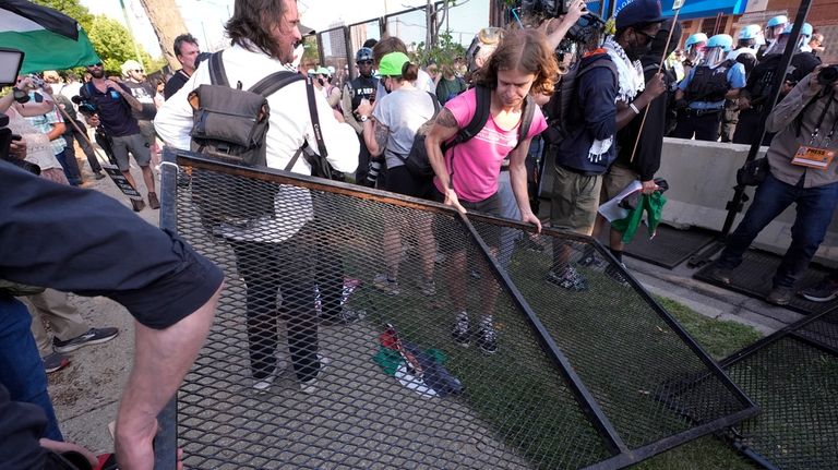 Protesters knock down a fence surrounding United Center at the...