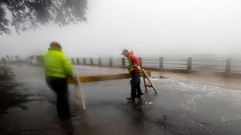 Police set up a barricade on a flooded street in...