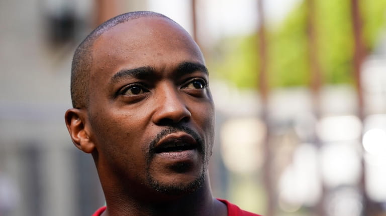 Actor Anthony Mackie speaks outside a home while working with...