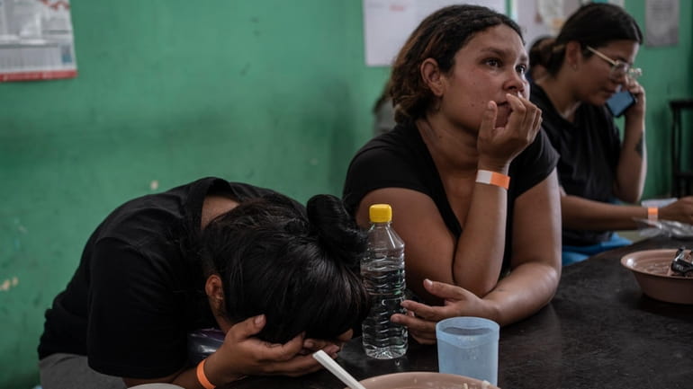 Yeneska Garcia, a Venezuelan migrant, cries into her hands as...