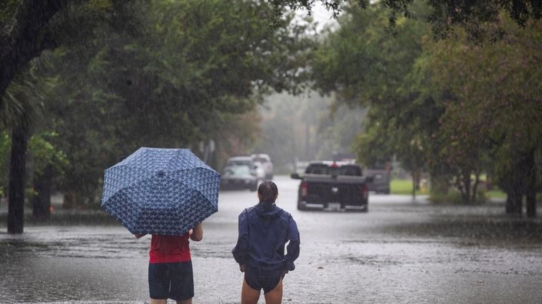 People wade into the flood waters overcoming Gordon Street as...