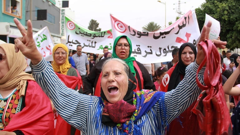 Tunisians take part in a protest against the presence of...