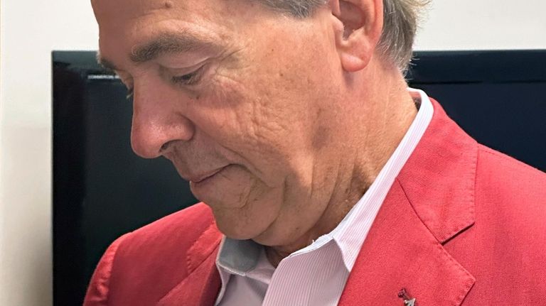 Alabama NCAA college football head coach Nick Saban examines one...