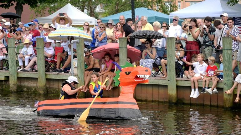 People lined the waterfront to watch as racers paddle by in...