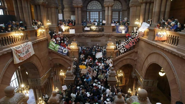 People gather to protest cuts in the New York State...