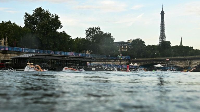 Athletes compete in the swimming race in the Seine River...