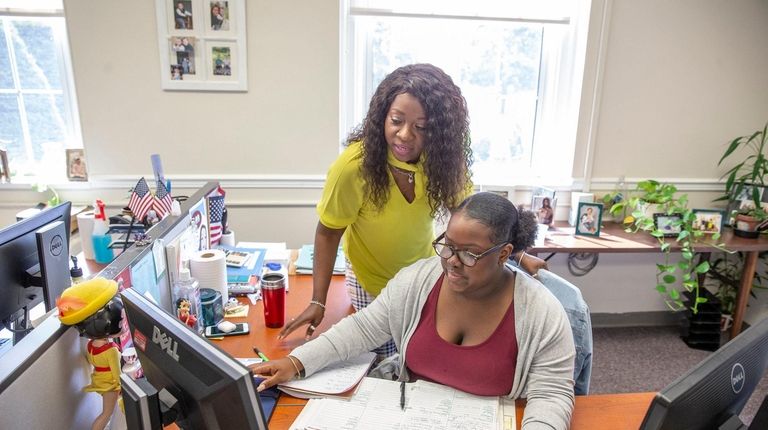 Intern Nicole Williams, seated, gets some help from Maureen Bailey-Treco at the...