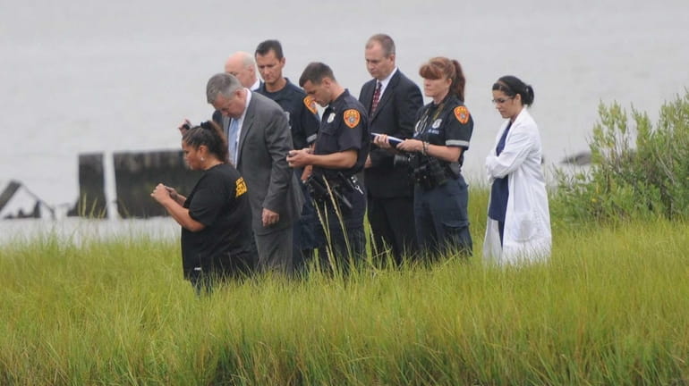 Suffolk County homicide detectives, along with a medical examiner, investigate...