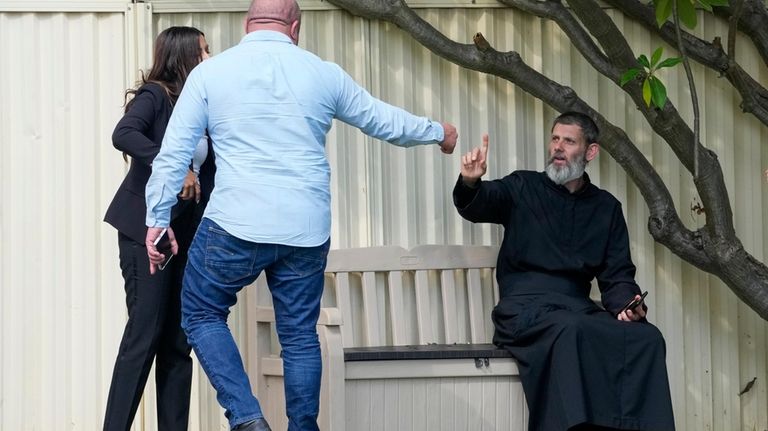 Father Daniel Kochou, right, gestures as he speaks with people,...