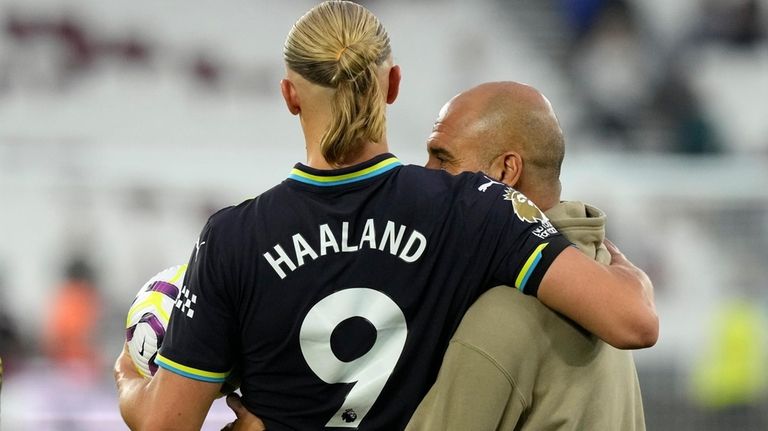 Manchester City's head coach Pep Guardiola hugs Manchester City's Erling...