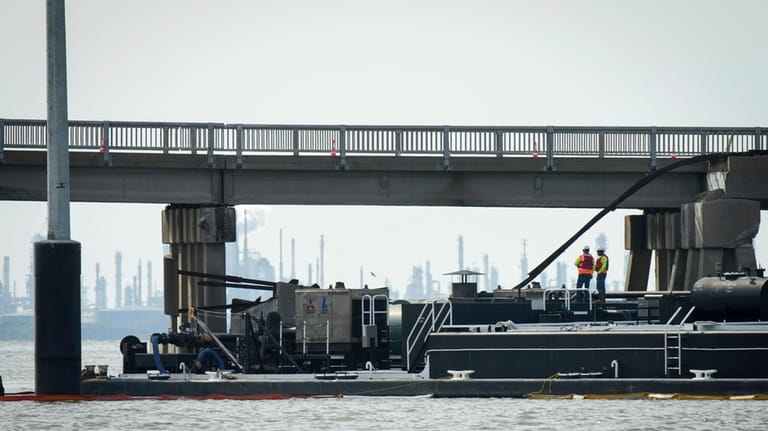Two workers stand on the barge that struck the Pelican...