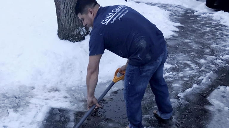 Cristhian Ramos, 30, of Huntington, shovels his driveway Monday morning...