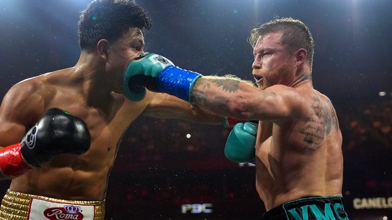 Canelo Alvarez, right, hits Jaime Munguia, left, during a super...