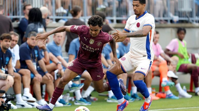 Manchester City's Oscar Bobb, left, works the ball past Chelsea's...