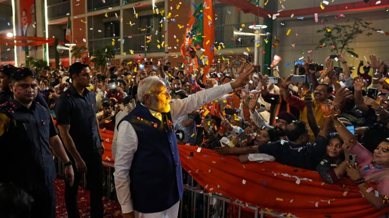 Prime Minister Narendra Modi is greeted by supporters as he...