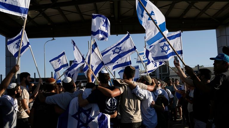 Protesters wave Israeli national flags in support of soldiers being...