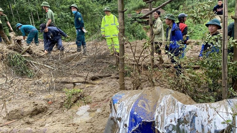 Rescue workers clear mud and debris brough down by a...