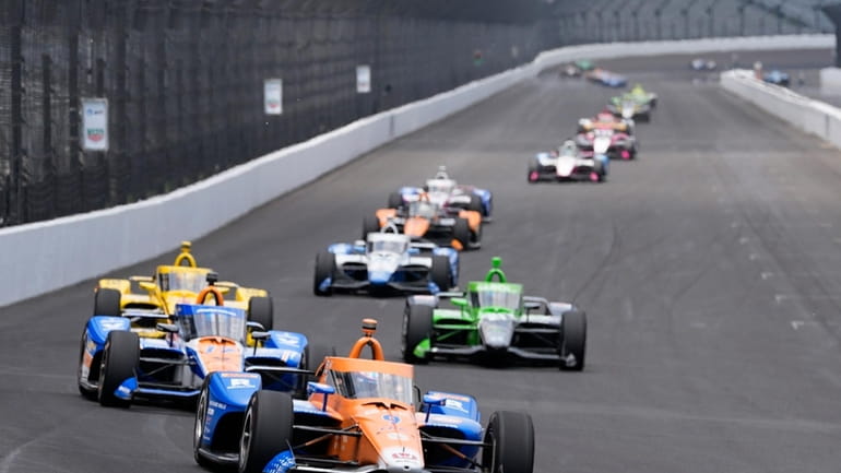 Scott Dixon, of New Zealand, leads a pack of cars...