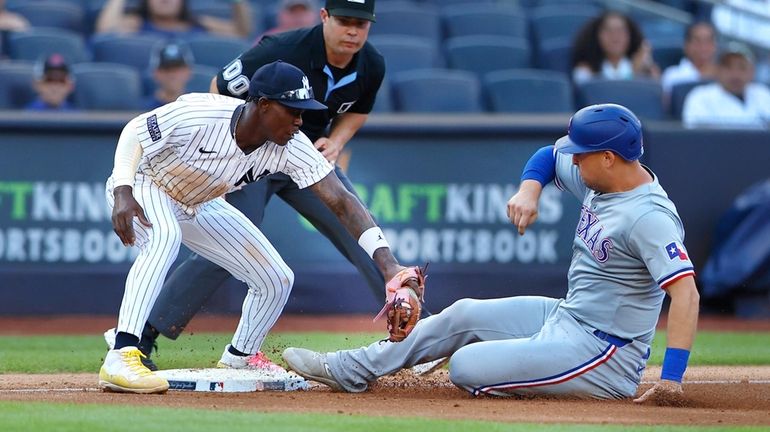 The Rangers' Wyatt Langford, right, beats a tag by the Yankees'...