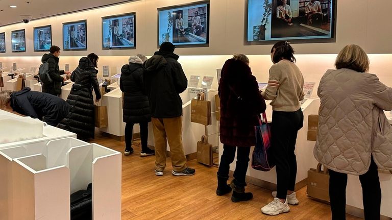 Shoppers at a Uniqlo store in New York use self-checkout...