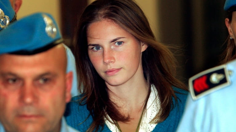Amanda Knox, center, is escorted by Italian penitentiary police officers...