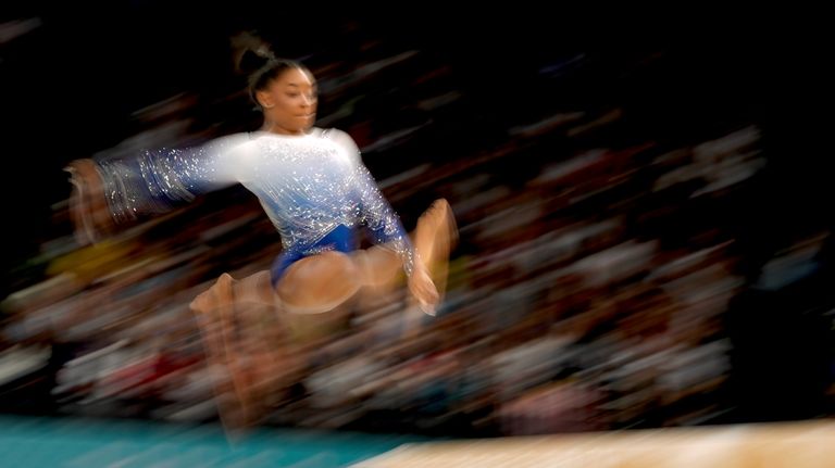 In this photo made with a slow exposure, Simone Biles,...