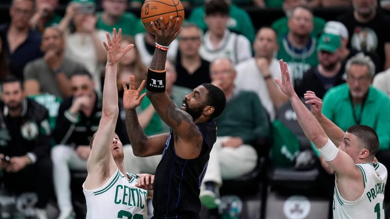 Dallas Mavericks guard Kyrie Irving, center, shoots as Boston Celtics...
