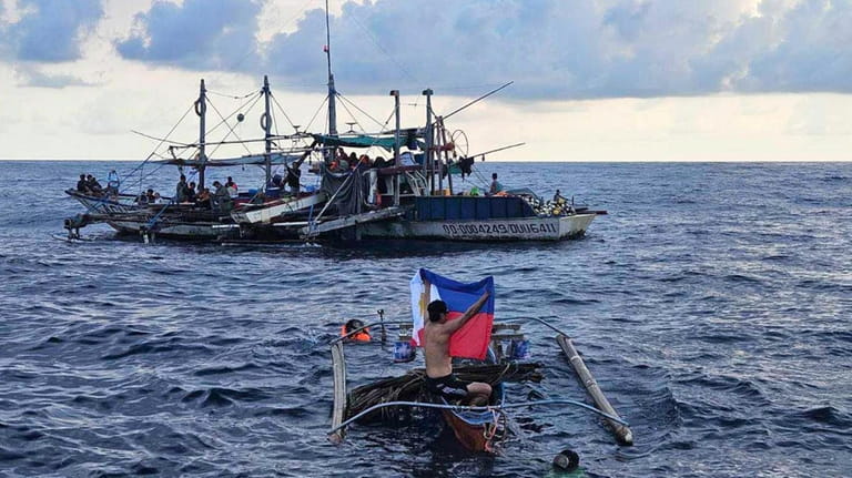 In this photo provided by Atin-Ito/Akbayan Party, a fisherman raises...