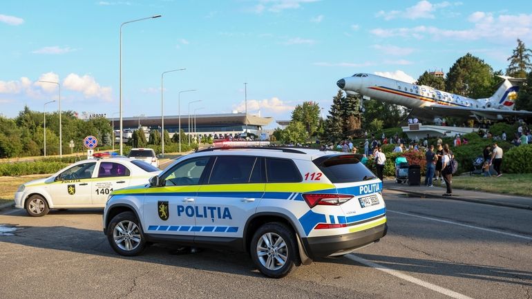 Travelers stand outside the Chisinau airport in Moldova Friday, June...