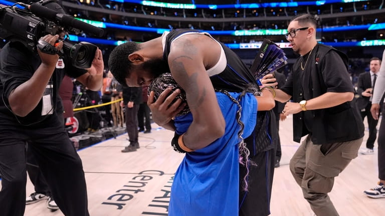 Dallas Mavericks' Kyrie Irving hugs his child after the team's...