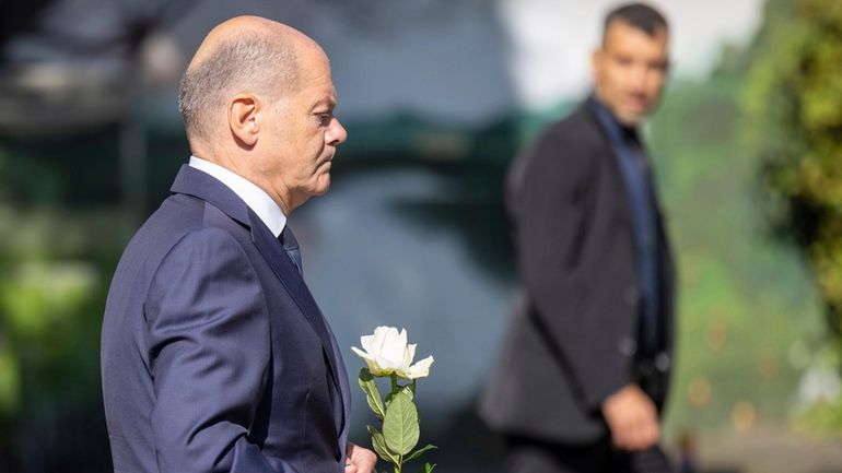 Germany Chancellor Olaf Scholz lays a flower at a church,...