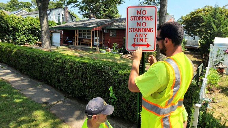 Massapequa Park workers on Wednesday install No Stopping signs in front...