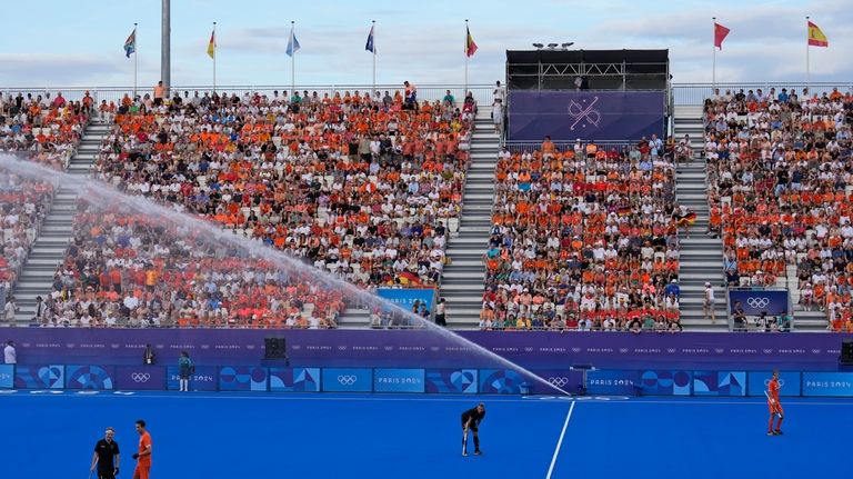 Germany's Niklas Wellen, center, stands under an arc of water...