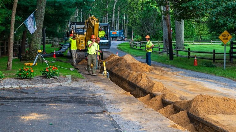 Workers install new water lines in Manorville along Wading River...