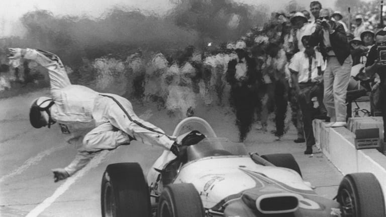 Parnelli Jones dives out of his car after it caught...