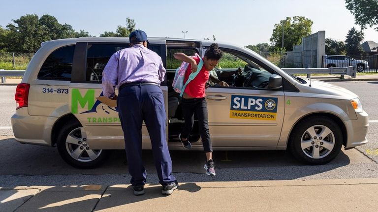 A student is helped out of a transportation service vehicle...