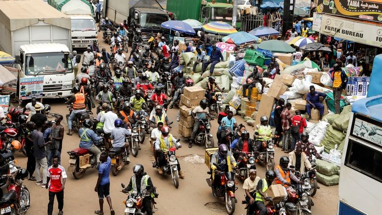 Drivers of motorcycle taxis, known locally as boda-bodas, ride with...